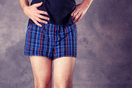 man in blue plaid boxer shorts in front of gray backgroundの写真素材
