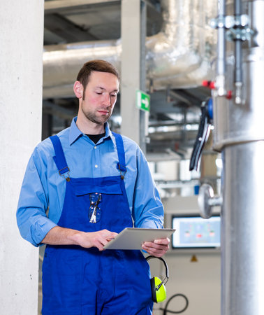 worker in blue workweare with tablet compute  in industrial plantの写真素材