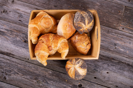 different fresh rolls and croissants in wooden basketの写真素材