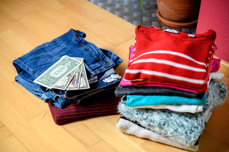 pile of second hand clothing and  shoes with money on floor in living roomの写真素材