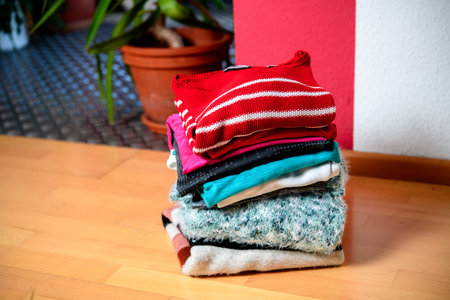 pile of second hand clothing on floor in living roomの写真素材