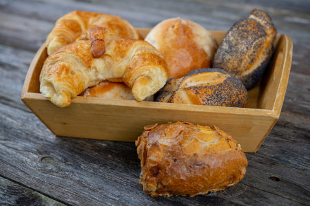 different fresh rolls and croissants in wooden basketの写真素材