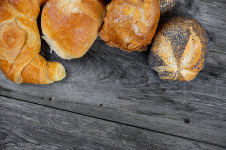 different fresh rolls and croissants on wooden ground
