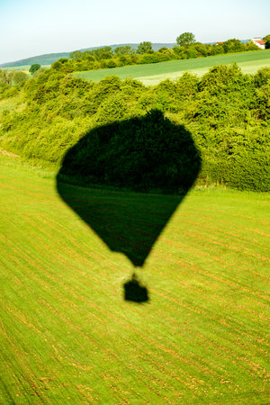 shadow of a hot- air balloon on green landscape from aboveの写真素材