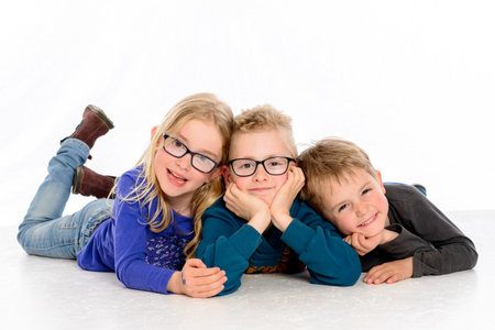 three happy children in front of white backgroundの写真素材
