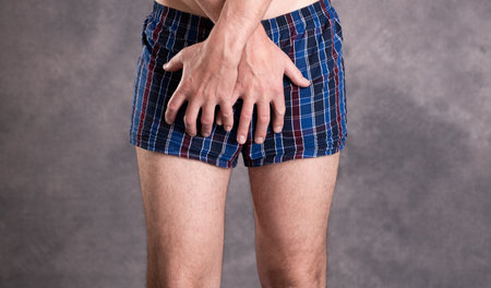 man in blue plaid boxer shorts in front of gray backgroundの写真素材