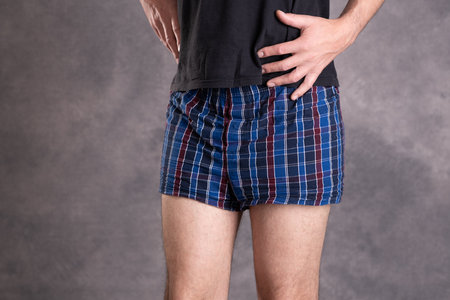 man in blue plaid boxer shorts in front of gray backgroundの写真素材