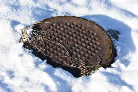 SANITARY SEWER COVER IRON UNDER THE SNOWの写真素材