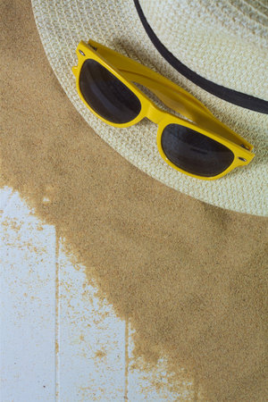 Sunglasses and hat on beach sand and woodの写真素材