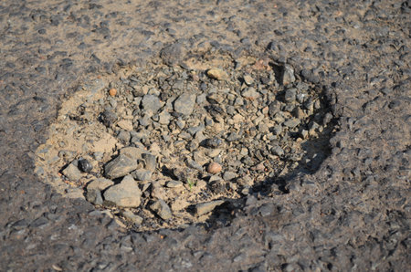 Old cracked asphalt floor with a bummer and a concrete underの写真素材