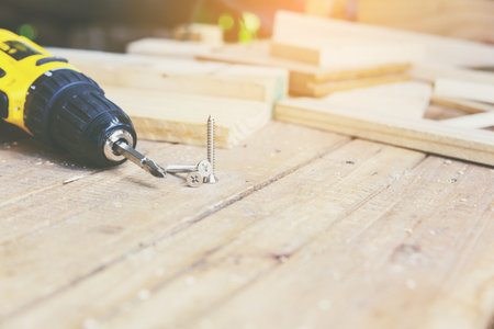 Wireless electric drill with screw on wooden table,diy at home concept.の写真素材