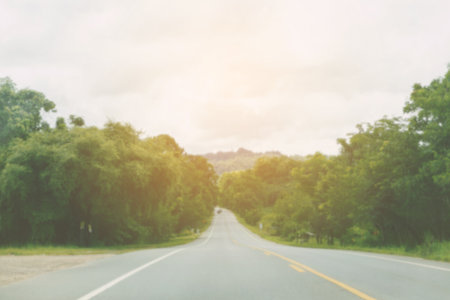 Blur long local road around with green tree with nimbus cloud,take a photo inside a car for background use.の写真素材