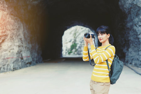 Young Woman in yellow sweater take a photo between travel in mountain cave.の写真素材