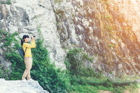 Young Woman in yellow sweater take a photo between travel in mountainの写真素材