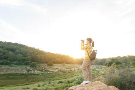 Young Woman in yellow sweater is take a photo for view of mountain between travel in vacation time.の写真素材