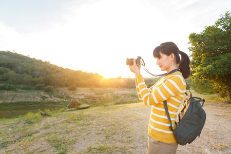 Young Woman in yellow sweater is take a photo for view of mountain between travel in vacation time.