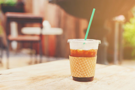 iced black coffee in a plastic glass put on the wooden table for refresh brain and body in the morning.の写真素材