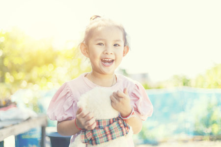 Little girl is smiling and holding her teddy bear between playing at outdoor.