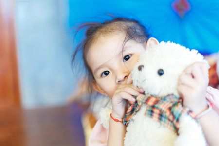 Little kid hiding a teddy doll between playing at indoor.の写真素材