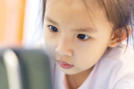 Child's watching a learning a lesson in tablet on the bed before bedtime.の写真素材