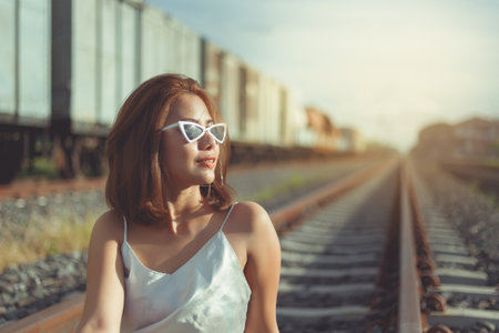 Fashionable woman in white dress shooting a photo between travelling at railway.retro style.の写真素材
