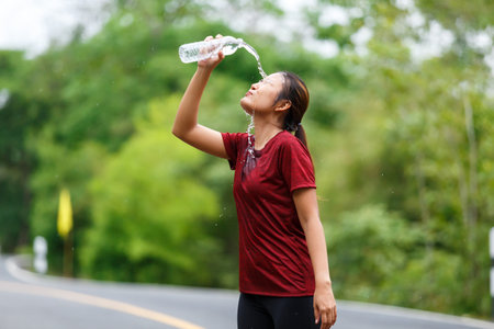 Woman runner's washing her  face with a water from the bottle after run.の写真素材