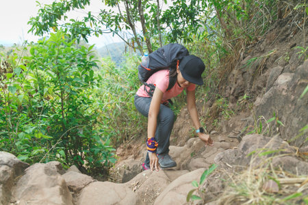 Woman claim a rock mountain between trekking in the Thai forest.