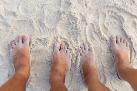 Couple feet standing on white sand beachの写真素材