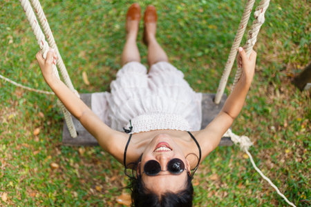 Woman playing a swing on green yard, selective focus.の写真素材