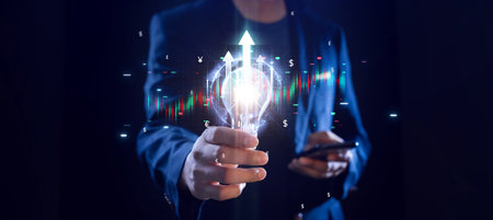 Businessman holding a bright light bulb stock investment graph world economic growthの写真素材