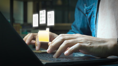Close-up of hands typing on a laptop with holographic digital documents and a folder icon floating above, representing file management, data organization, and online documentation.の写真素材