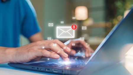 Close-up of hands typing on a laptop keyboard with floating email icons and notification alerts. Concept of digital communication, email management, and technology in modern work.の写真素材