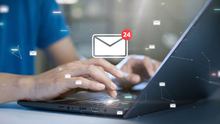 Close-up of hands typing on a laptop keyboard with floating email icons and a notification symbol. Concept of digital communication, online messaging, and email notifications.の写真素材