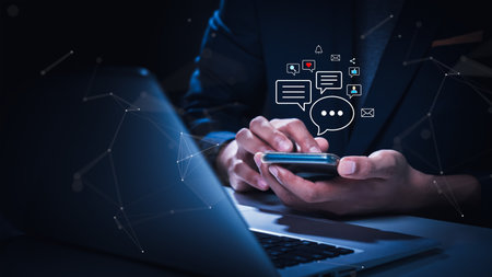 Businessman using smartphone for online messaging, surrounded by digital communication icons, illustrating modern connectivity and real-time interaction.の写真素材