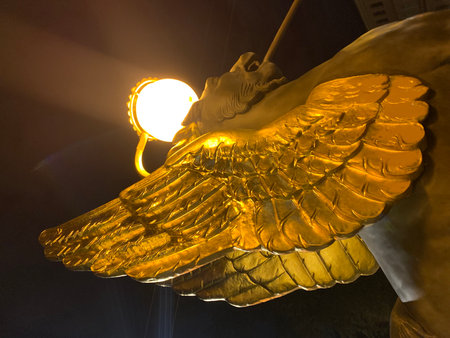 Golden angel wings with a lantern in the background, illuminated by a street lightの写真素材