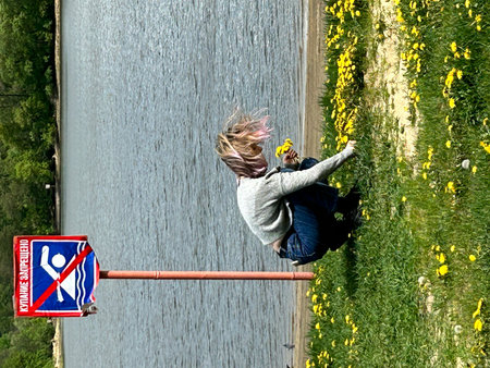 Young woman crossing the bridge over the canal. Tsna, Tambov, dandelions, wind, springの写真素材