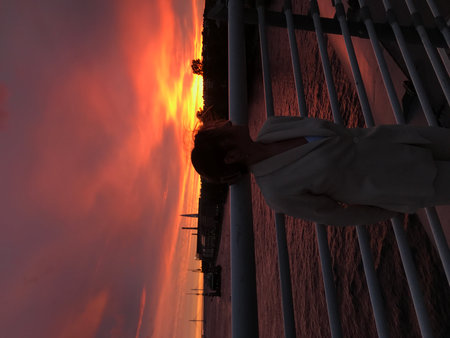 A woman in a white robe looks at the sunset from the balcony of a ship. Sunset, St. Petersburgの写真素材