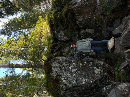 A young woman is resting on a rock in the forest. View from above. Ruskeala, Karelia, Marble Canyon, Mountain Parkの写真素材