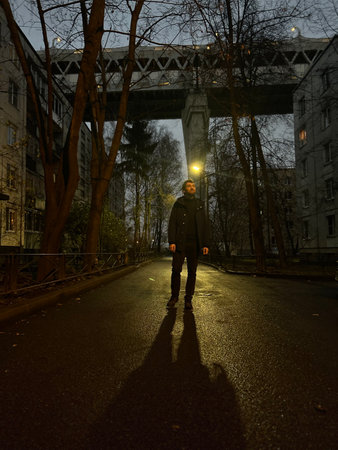 A young man walking under a bridge at night. Kanonersky Island, St. Petersburg