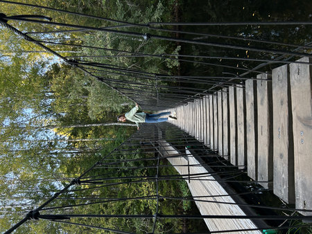 A man on a suspension bridge over the river in the forest.の写真素材