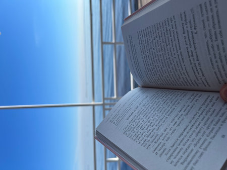 A book in front of a blue sky and a glass building.の写真素材