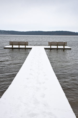 Bathing jetty with two benches covered with snowの写真素材