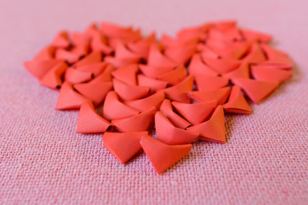 many mini red paper hearts origami sort to heart shape on a pink fabric backgroundの写真素材