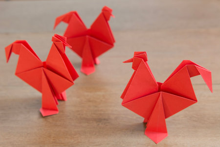 a group of red origami chicken on wooden background close upの写真素材