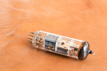 vacuum tube, old electronic component part laying on genuine leather surface close up