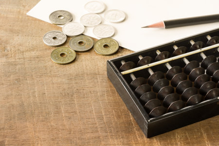 blur old japanese style abacus coins pencil and blank paper on wooden table with copy space....