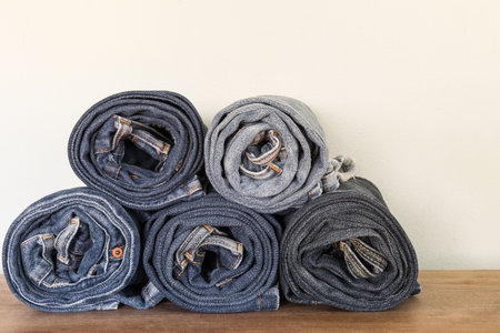 stack of roll old fade denim on wooden surface and concrete background. vintage clothing fashion concept.の写真素材