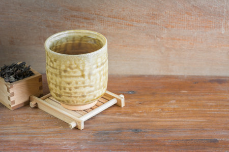 cup of chinese tea with bamboo coaster on old and crack wooden table. healthy beverage concept.の写真素材