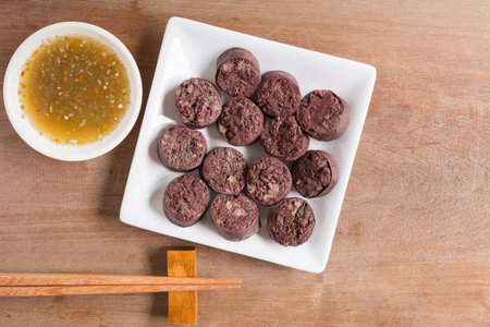 vietnamese style cooked blood and vegetable sausage in ceramic plate  served with spicy sauce on wooden table. delicious food menu.の写真素材