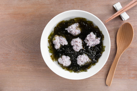 top view of pork ball and seaweed clear soup in a ceramic bowl on wooden table. asian homemade style food concept.の写真素材